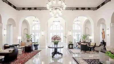 Grand colonial lobby at Raffles Hotel Le Royal Phnom Penh featuring arched colonnades, chandeliers, and heritage-era elegance