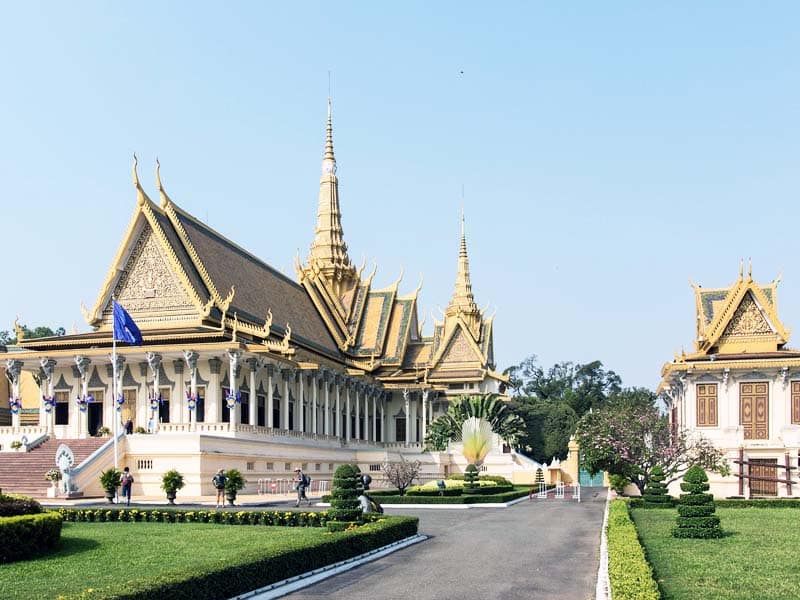 Royal Palace complex in Phnom Penh featuring ornate Khmer architecture, manicured gardens, and ceremonial courtyards under clear skies