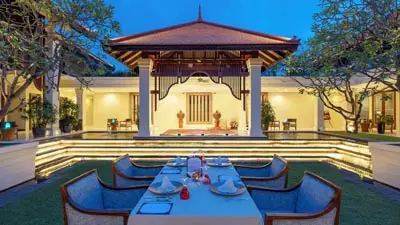 Anantara Angkor Resort Siem Reap courtyard dining pavilion at dusk, featuring a candlelit private dinner setup beside a serene reflecting pool and elegant Khmer-inspired architecture.