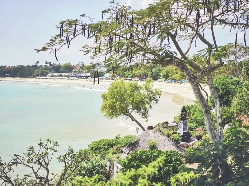 Panoramic ocean and beach view from Four Seasons Jimbaran Bay overlooking calm turquoise waters and tropical hillside garden