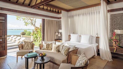 Luxury ocean-view villa suite at Four Seasons Jimbaran Bay featuring canopy bed, open-air living space, and private terrace overlooking the Indian Ocean