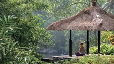 Open-air riverside yoga pavilion at Four Seasons Sayan Ubud surrounded by lush jungle rainforest and tranquil river valley scenery