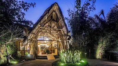 Night view of Munduk Moding Plantation in North Bali, showcasing elevated bamboo architecture surrounded by jungle foliage, a secluded luxury accommodation set in the highland rainforest