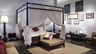 Luxury suite with four-poster canopy bed and elegant Lao-inspired décor at Sofitel Luang Prabang, a heritage boutique hotel in Luang Prabang, Laos.