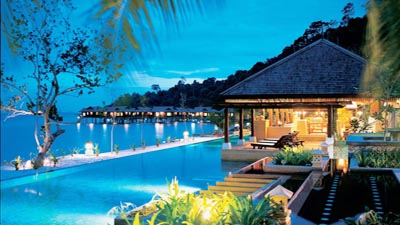 Overwater villas and infinity pool at Pangkor Laut Resort in Malaysia, overlooking a tranquil private island bay at dusk