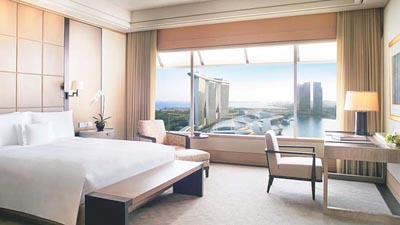 Marina Bay view guest room at The Ritz-Carlton, Millenia Singapore with contemporary furnishings and expansive city views.