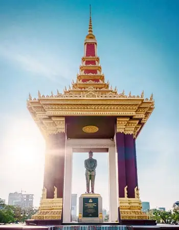Independence Monument in Phnom Penh, Cambodia, golden Khmer-style memorial pavilion honoring King Norodom Sihanouk against a clear blue sky in the city center.