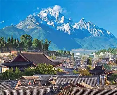Lijiang Old Town rooftops with Jade Dragon Snow Mountain rising in the background, showcasing Yunnan’s cultural and scenic beauty.