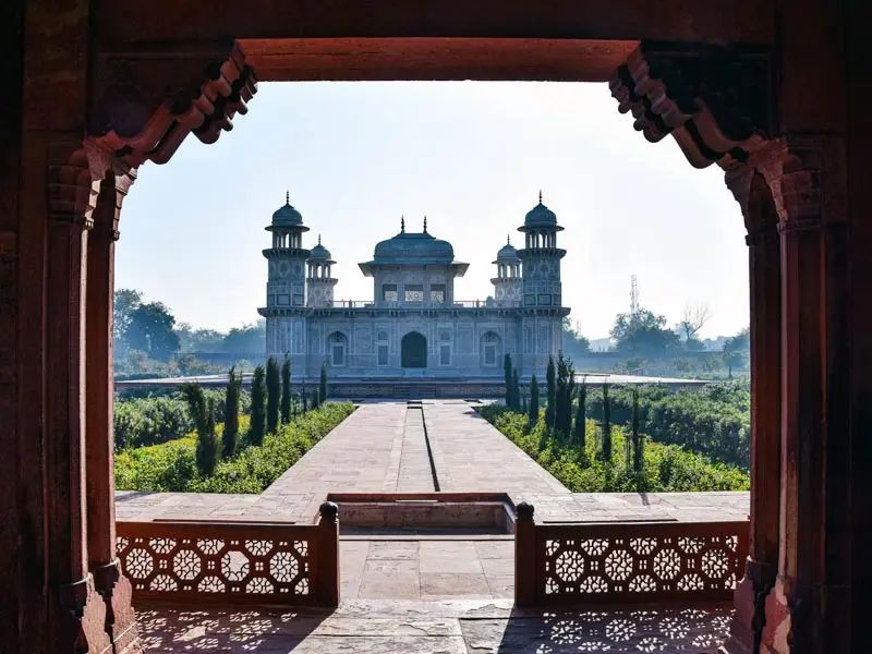 Elegant view of Itimad-ud-Daulah’s Tomb in Agra, framed by carved sandstone arches and Mughal gardens under soft morning light.