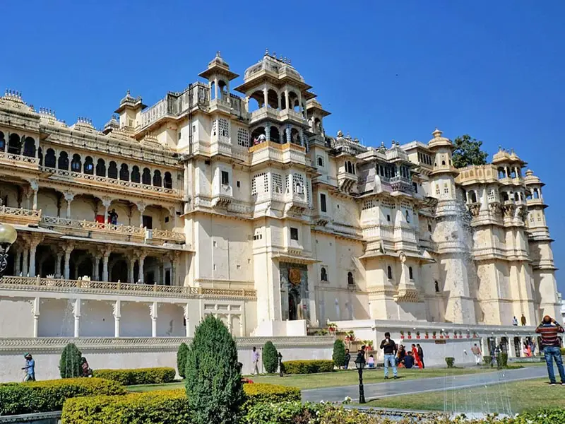 City Palace Udaipur exterior with ornate Rajput architecture, courtyards, and visitors exploring the historic lakeside royal complex in Rajasthan, India