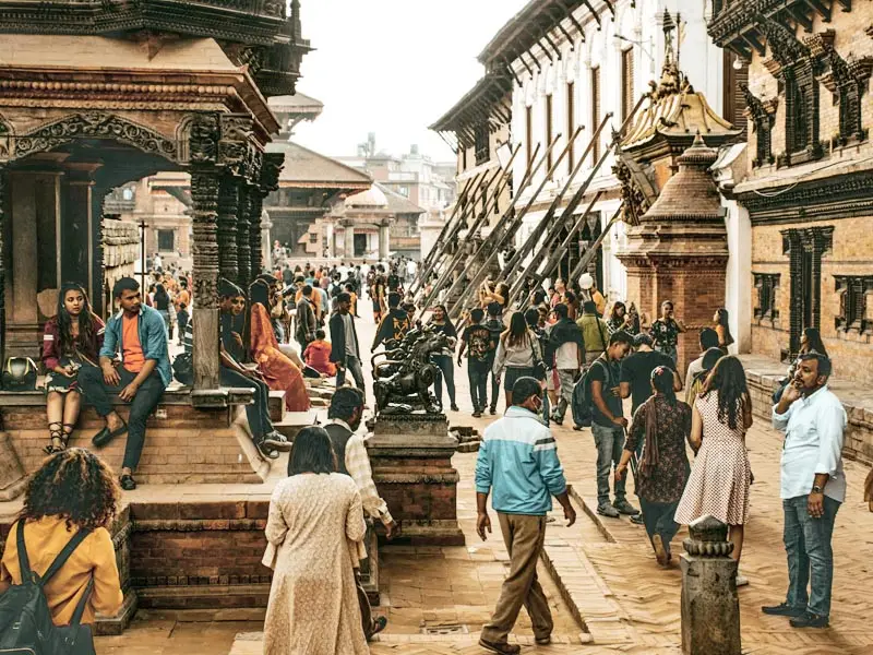 Crowds exploring Patan Durbar Square in Kathmandu Valley, Nepal, surrounded by traditional Newari temples, palaces, and intricate historic architecture.