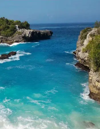 Turquoise waves crashing against rugged limestone cliffs near Seminyak, Bali, showcasing the island’s dramatic coastline and tropical seaside beauty.
