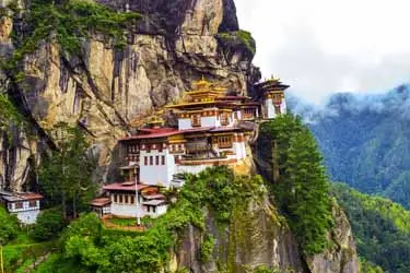 Tiger’s Nest Monastery (Paro Taktsang) in Bhutan, dramatically perched on a cliffside above forested mountains.