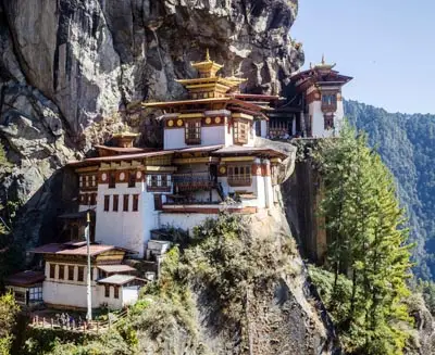Tiger’s Nest Monastery (Paro Taktsang) perched on a cliffside in Bhutan, surrounded by forested mountains, showcasing traditional Bhutanese architecture.