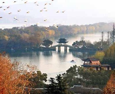 West Lake in Hangzhou with pagodas, autumn trees, and calm water, showcasing one of China’s most celebrated scenic landscapes.