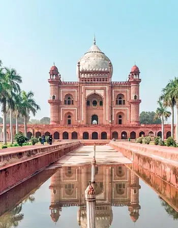 Front view of Safdarjung Tomb in New Delhi, India, with symmetrical Mughal architecture, palm trees, and reflection in the water channel.