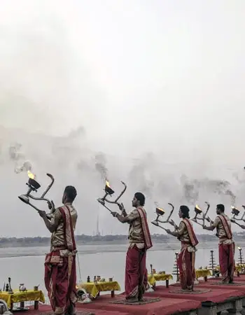 Hindu priests performing Ganga Aarti with traditional lamps on the ghats of Varanasi, India, by the Ganges River during a spiritual ceremony.