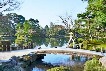 Traditional stone bridge and landscaped pond in Kenrokuen Garden, Kanazawa