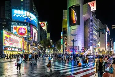 Vibrant nighttime scene at Shibuya Crossing with towering screens and city lights