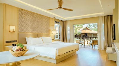Spacious beachfront room at Pelangi Beach Resort & Spa Langkawi, Malaysia, featuring tropical décor and a private balcony overlooking island villas