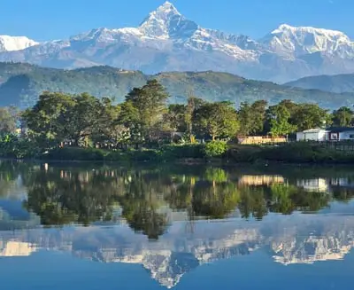 Stunning view of Machapuchare (Fishtail Mountain) and the Annapurna range reflected in the calm waters of Phewa Lake in Pokhara, Nepal.