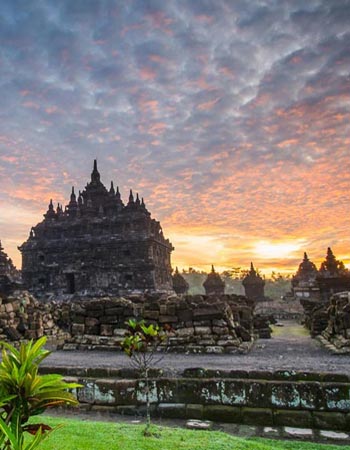 Prambanan Temple complex at sunrise in Yogyakarta, Indonesia, showcasing towering Hindu temple spires against a dramatic morning sky.