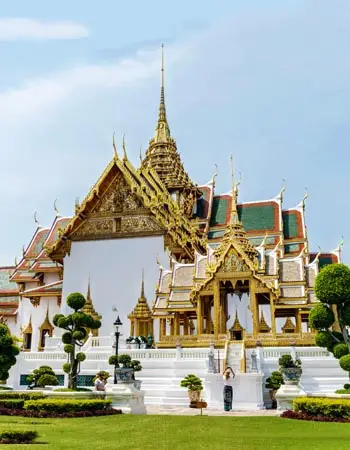 Grand Palace in Bangkok, Thailand, featuring ornate golden spires and traditional Thai architecture set within manicured royal grounds.