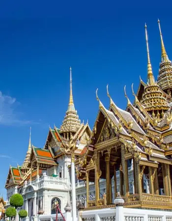 Wat Phra Kaew (Temple of the Emerald Buddha) in Bangkok, Thailand, showcasing ornate golden spires and intricate Thai temple architecture under a clear blue sky.
