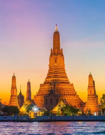 Wat Arun (Temple of Dawn) in Bangkok, Thailand, glowing at sunset with its iconic central prang rising above the Chao Phraya River.