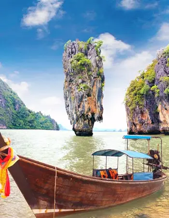 Long-tail boat anchored near Ko Tapu (James Bond Island) in Phang Nga Bay, Thailand, with iconic limestone karst rising from shallow emerald waters.