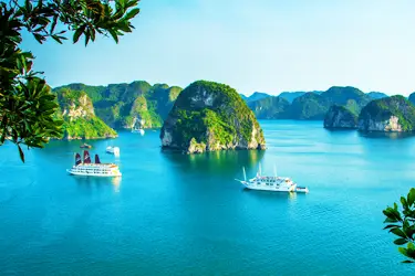 Cruise ships sailing through the emerald waters of Ha Long Bay, Vietnam, surrounded by towering limestone karsts in this iconic UNESCO World Heritage seascape.