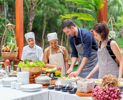 Travelers participating in a Vietnamese cooking class with local chefs, preparing fresh ingredients and learning traditional culinary techniques in an immersive cultural experience.