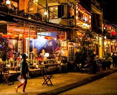 Lantern-lit street with lively cafés and restaurants in Hoi An, Vietnam, capturing the town’s romantic evening atmosphere and well-preserved historic charm.