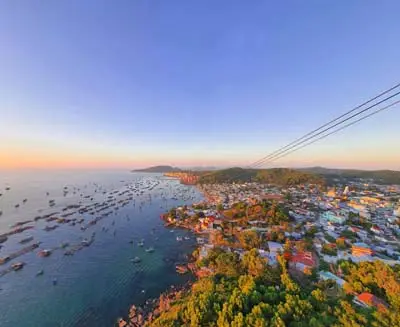 Aerial view of Phu Quoc Island’s coastline at sunset, revealing colorful fishing boats, seaside villages, and Vietnam’s laid-back tropical charm.