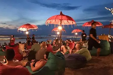 Beachfront lounge at sunset with umbrellas and bean bags on Seminyak Beach.