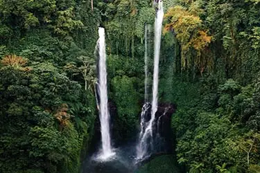 Twin waterfalls cascading through lush jungle in Munduk.