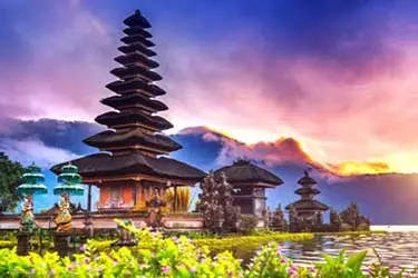 Ulun Danu Beratan Temple at sunset on Lake Beratan in Bali with tiered pagoda and mountain backdrop.