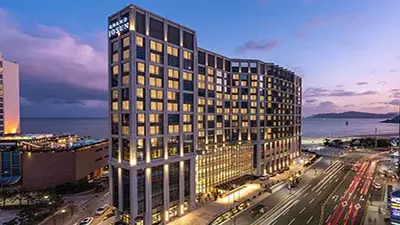Grand Josun Busan hotel exterior at dusk along Haeundae Beach, featuring modern luxury architecture, illuminated facade, and coastal city views in Busan, South Korea.