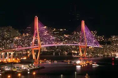 Gwangan Bridge illuminated at night over Busan Harbor, showcasing the vibrant skyline and coastal cityscape of Busan, South Korea.