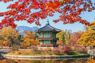 Hyangwonjeong Pavilion at Gyeongbokgung Palace in Seoul, South Korea, surrounded by vibrant autumn foliage and reflected in a tranquil pond.
