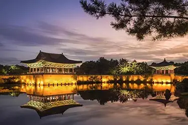 Donggung Palace and Wolji Pond illuminated at night in Gyeongju, South Korea, reflecting historic Silla-era architecture across tranquil water.