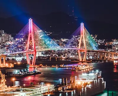 Gwangan Bridge illuminated in colorful lights over Busan Harbor at night, a famous landmark of Busan’s vibrant coastal skyline in South Korea.