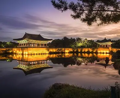 Donggung Palace and Wolji Pond illuminated at night in Gyeongju, South Korea, reflecting historic Silla-era architecture across tranquil water.