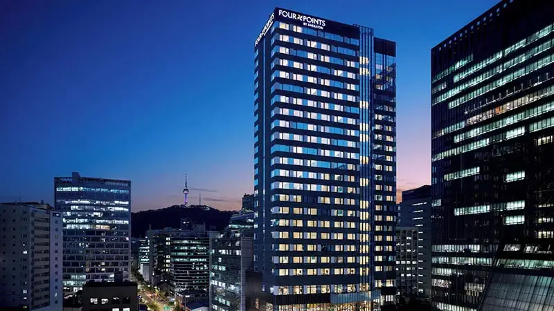 Exterior of Four Points by Sheraton Josun Seoul at dusk, a sleek high-rise tower illuminated against the city skyline with views toward Namsan and N Seoul Tower.