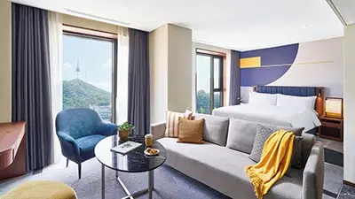 Stylish guest room at voco Seoul Myeongdong by IHG featuring modern furnishings, large windows with N Seoul Tower views, and contemporary boutique hotel design in central Seoul.