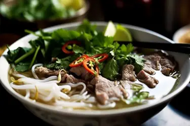 Steaming bowl of Vietnamese pho with tender beef, fresh herbs, bean sprouts, and chili, showcasing one of Vietnam’s most iconic and beloved culinary traditions.