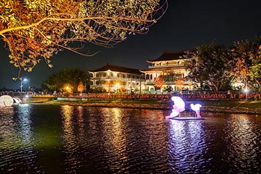 Nighttime waterfront scene in Tainan, Taiwan, featuring illuminated traditional architecture, glowing reflections across calm water, and a peaceful historic atmosphere.