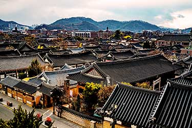 Traditional hanok rooftops stretching across the historic Hahoe Folk Village in Andong, South Korea, showcasing preserved Korean architecture against a scenic mountain backdrop.