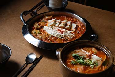 Traditional Korean stew and hot pot dishes featuring tofu, mushrooms, vegetables, and spicy broth, showcasing the comforting flavors of South Korean cuisine.