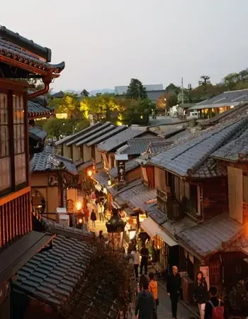 Japan_350-450_Kiso_Valley Lantern-lit street in Kiso Valley, a historic Japanese town, with families walking past traditional wooden houses at dusk.
